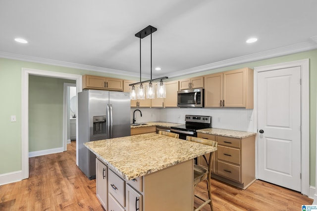 kitchen with appliances with stainless steel finishes, ornamental molding, sink, a kitchen island, and hanging light fixtures