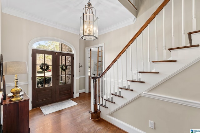 entrance foyer featuring a chandelier, french doors, dark hardwood / wood-style flooring, and ornamental molding