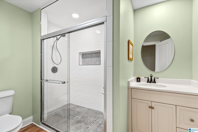 bathroom featuring wood-type flooring, vanity, toilet, and walk in shower