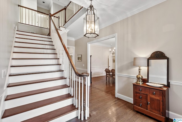 stairway featuring crown molding, hardwood / wood-style flooring, and a notable chandelier