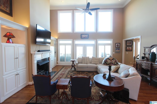 living room featuring ceiling fan, a towering ceiling, a high end fireplace, and a healthy amount of sunlight