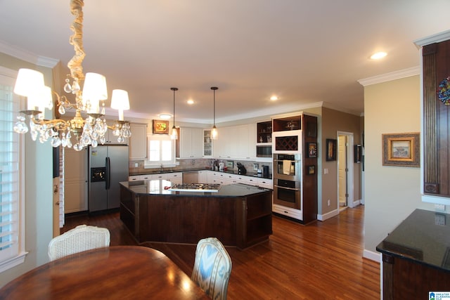 kitchen with pendant lighting, a center island, decorative backsplash, white cabinetry, and stainless steel appliances