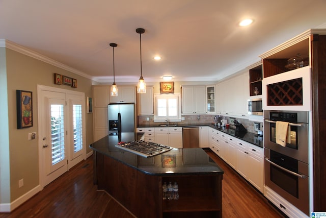 kitchen with pendant lighting, backsplash, sink, a kitchen island, and stainless steel appliances