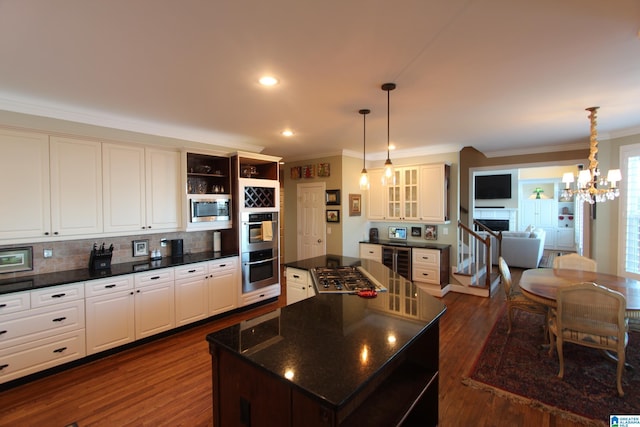 kitchen featuring hanging light fixtures, dark hardwood / wood-style floors, decorative backsplash, a kitchen island, and appliances with stainless steel finishes