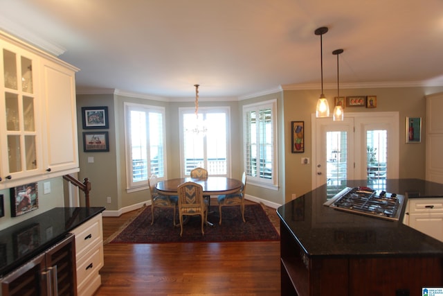 kitchen featuring white cabinets, dark hardwood / wood-style floors, hanging light fixtures, and ornamental molding