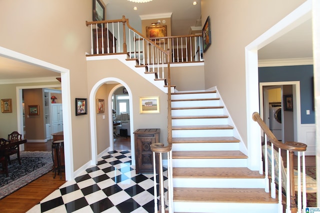 stairs with washer / dryer, crown molding, and a high ceiling