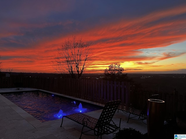 pool at dusk with a patio area and a fire pit