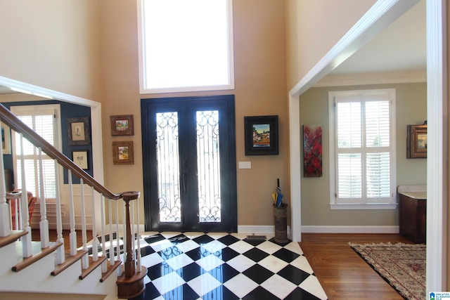 entrance foyer with french doors, dark hardwood / wood-style flooring, crown molding, and a high ceiling