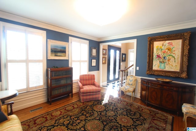 living area with hardwood / wood-style flooring and crown molding