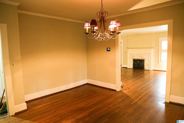 unfurnished room featuring a notable chandelier, ornamental molding, dark wood-type flooring, and a high end fireplace