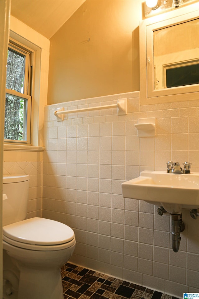 bathroom with toilet and tile walls