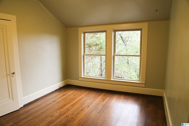 spare room featuring dark hardwood / wood-style flooring and lofted ceiling