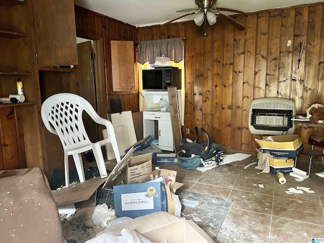 miscellaneous room with ceiling fan, wooden walls, and heating unit