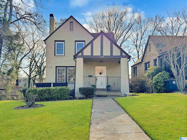 tudor-style house featuring a porch and a front lawn