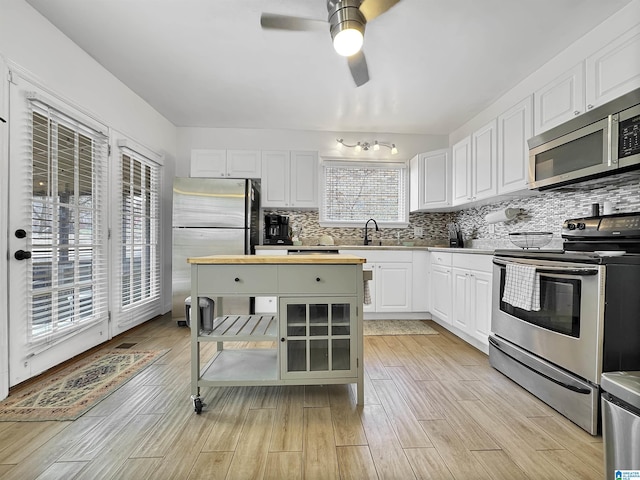 kitchen with backsplash, stainless steel appliances, white cabinetry, and sink