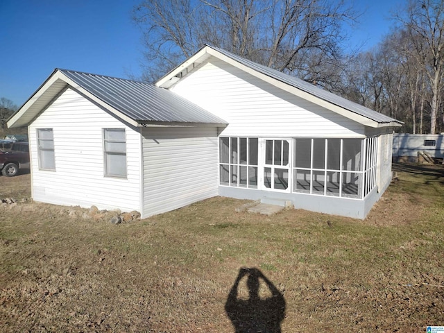 back of house with a sunroom and a lawn