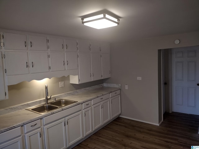 kitchen featuring white cabinets, light stone counters, sink, and dark wood-type flooring