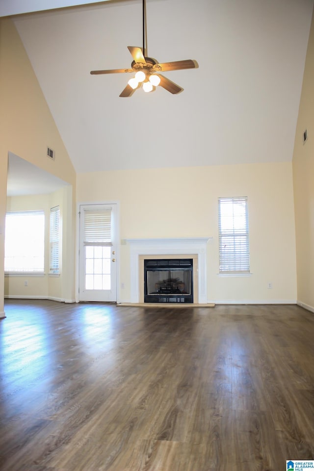 unfurnished living room with ceiling fan, plenty of natural light, dark hardwood / wood-style floors, and high vaulted ceiling