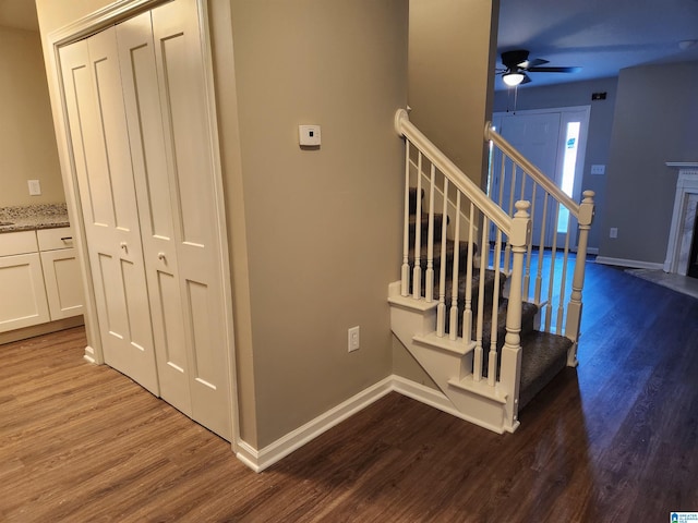 staircase with hardwood / wood-style flooring, a premium fireplace, and ceiling fan