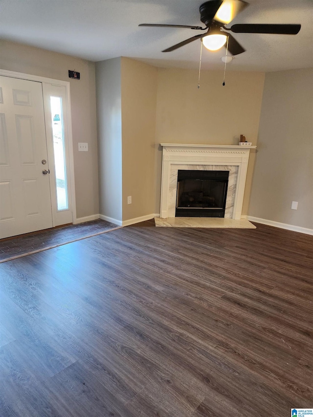 unfurnished living room with ceiling fan, a high end fireplace, and dark hardwood / wood-style flooring