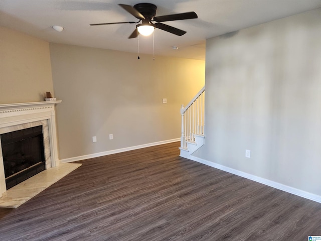 unfurnished living room with dark wood-type flooring, a tile fireplace, and ceiling fan