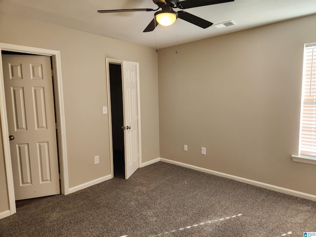 unfurnished bedroom featuring ceiling fan, dark carpet, and multiple windows