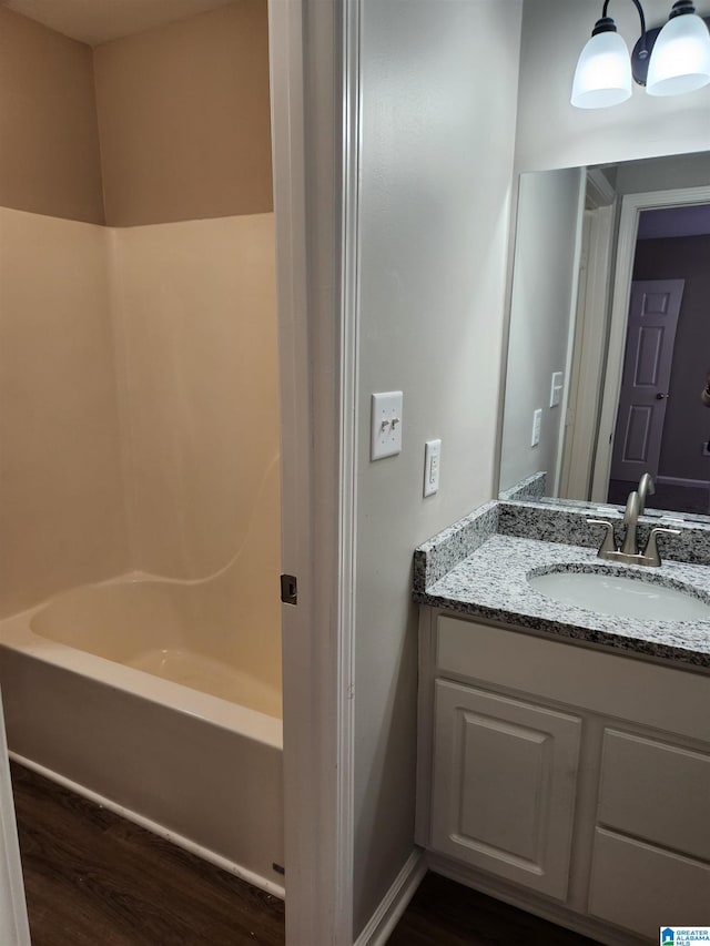 bathroom featuring hardwood / wood-style flooring, vanity, and  shower combination