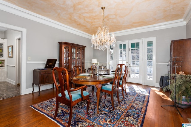 dining area with crown molding, french doors, a chandelier, and hardwood / wood-style flooring