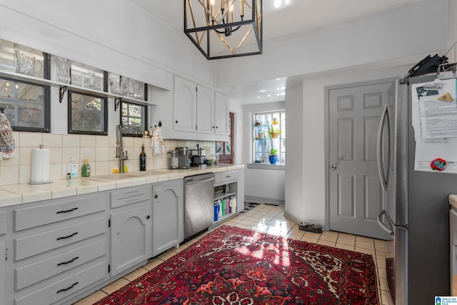 kitchen featuring sink, hanging light fixtures, decorative backsplash, tile counters, and stainless steel appliances