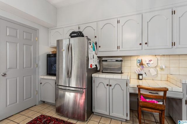 kitchen with white cabinets, decorative backsplash, stainless steel fridge, and light tile patterned flooring