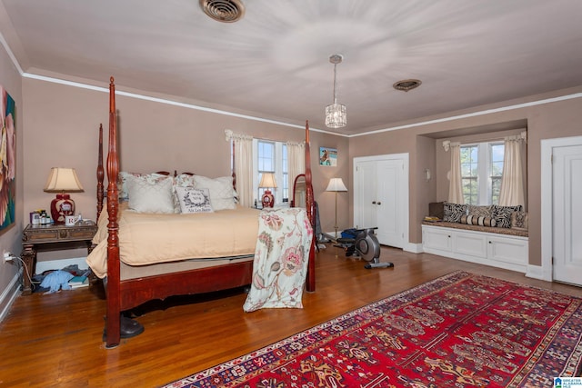 bedroom featuring hardwood / wood-style floors, crown molding, and multiple windows