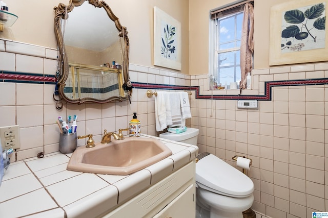 bathroom featuring walk in shower, vanity, toilet, and tile walls