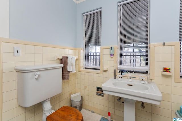 bathroom with toilet, ornamental molding, and tile walls