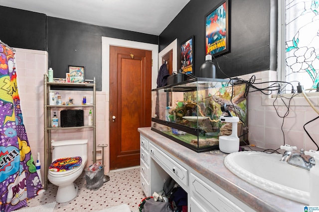 bathroom featuring toilet, vanity, tile patterned floors, and tile walls