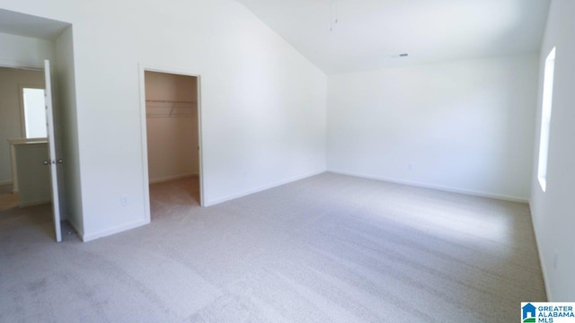 unfurnished bedroom with light carpet, multiple windows, a spacious closet, and a closet