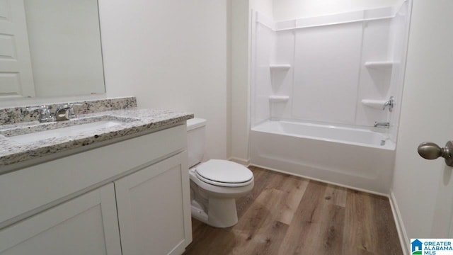 full bathroom with washtub / shower combination, hardwood / wood-style floors, vanity, and toilet