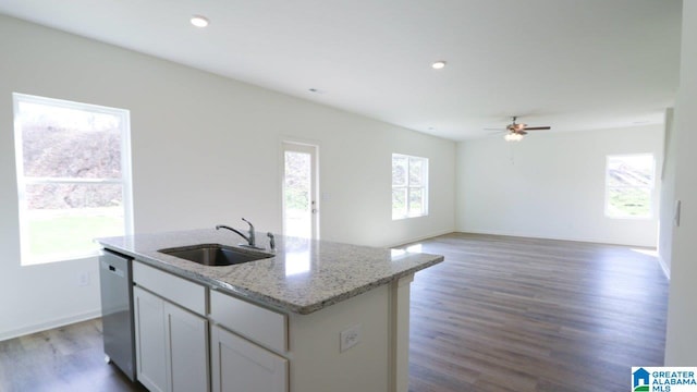 kitchen featuring light stone countertops, sink, dishwasher, dark hardwood / wood-style floors, and an island with sink