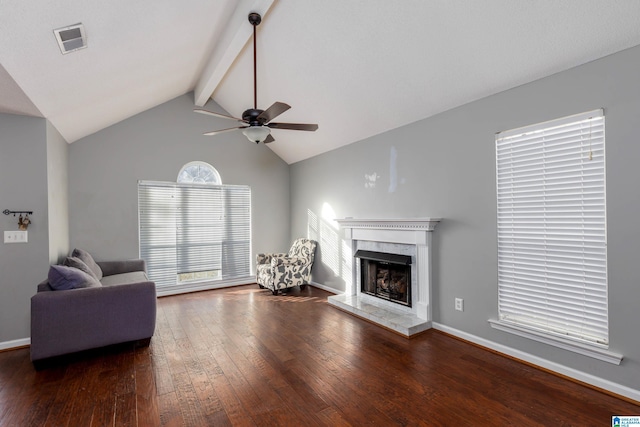 unfurnished living room featuring ceiling fan, dark hardwood / wood-style flooring, a premium fireplace, and vaulted ceiling with beams