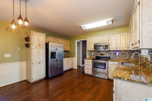 kitchen featuring stainless steel appliances, dark wood-type flooring, hanging light fixtures, stone counters, and sink