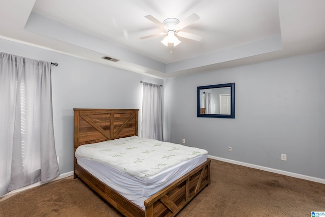 carpeted bedroom featuring ceiling fan and a raised ceiling