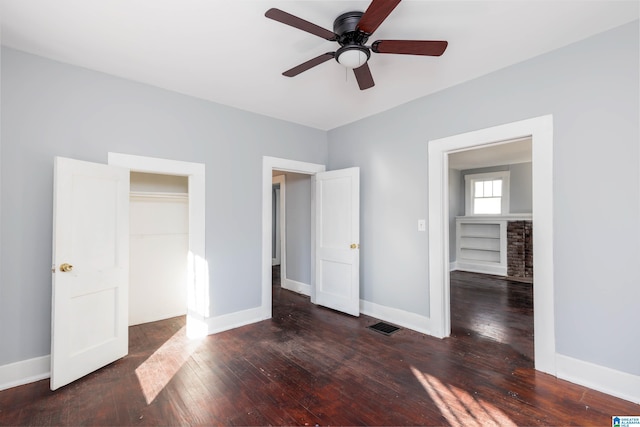 unfurnished bedroom featuring ceiling fan, a closet, dark wood-type flooring, and a spacious closet