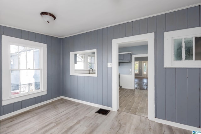 unfurnished room featuring crown molding, plenty of natural light, and light hardwood / wood-style floors