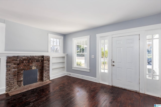 foyer entrance featuring dark hardwood / wood-style floors and a brick fireplace