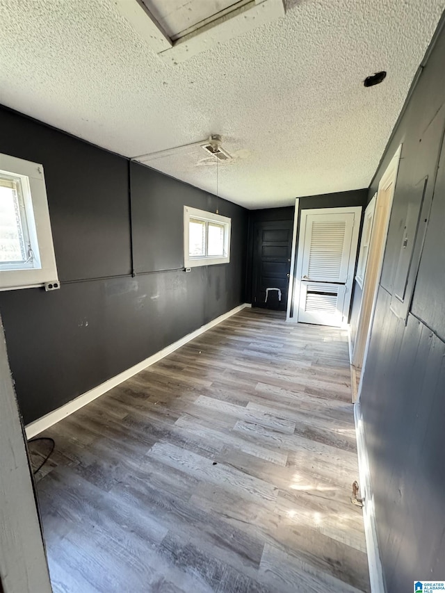 spare room with light wood-type flooring and a textured ceiling