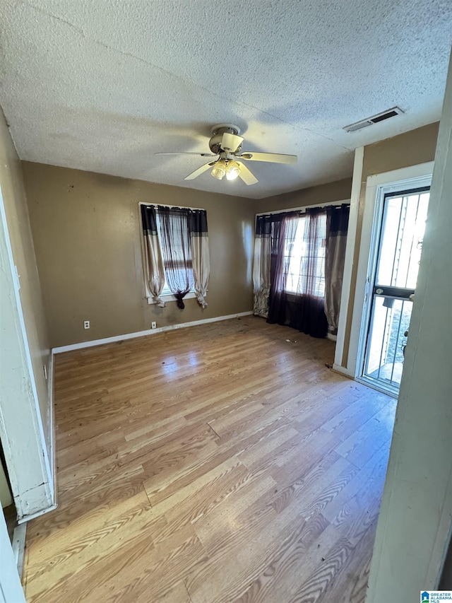 unfurnished room featuring ceiling fan, light hardwood / wood-style floors, and a textured ceiling