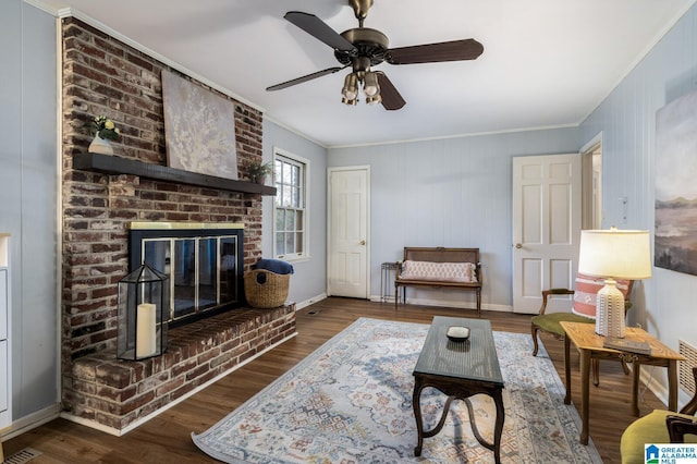 living room with ceiling fan, ornamental molding, dark wood-type flooring, and a brick fireplace