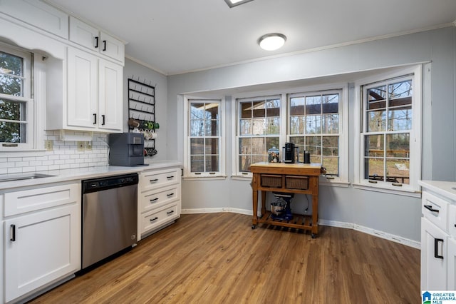 kitchen with backsplash, crown molding, hardwood / wood-style flooring, dishwasher, and white cabinetry