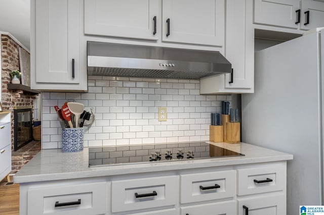 kitchen with white refrigerator, backsplash, ventilation hood, black electric cooktop, and white cabinets