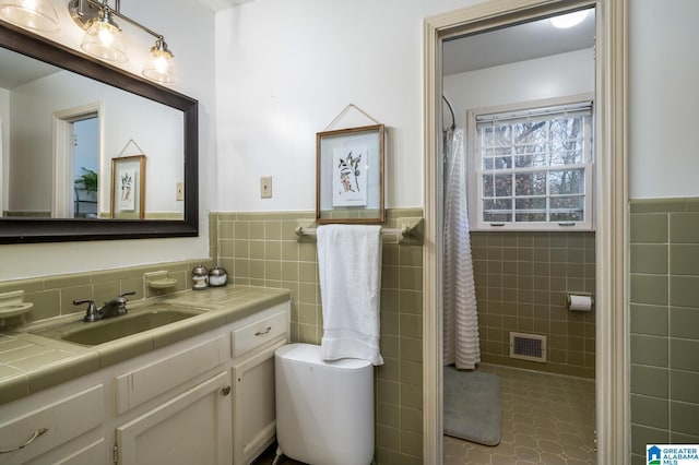 bathroom with vanity, tile patterned floors, toilet, tile walls, and curtained shower