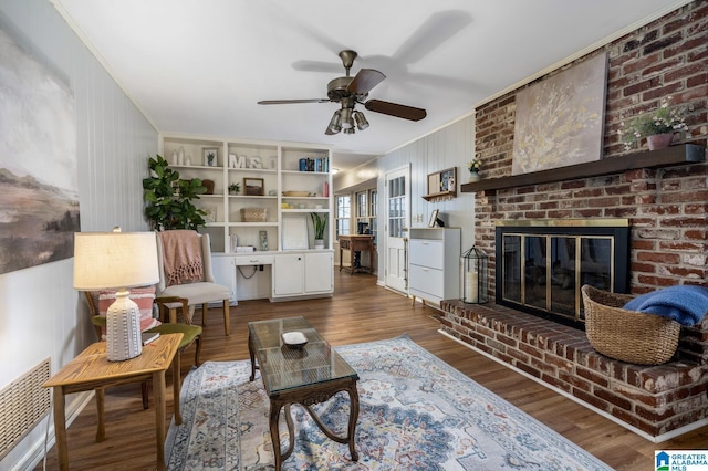 living room with ceiling fan, ornamental molding, dark wood-type flooring, and a brick fireplace